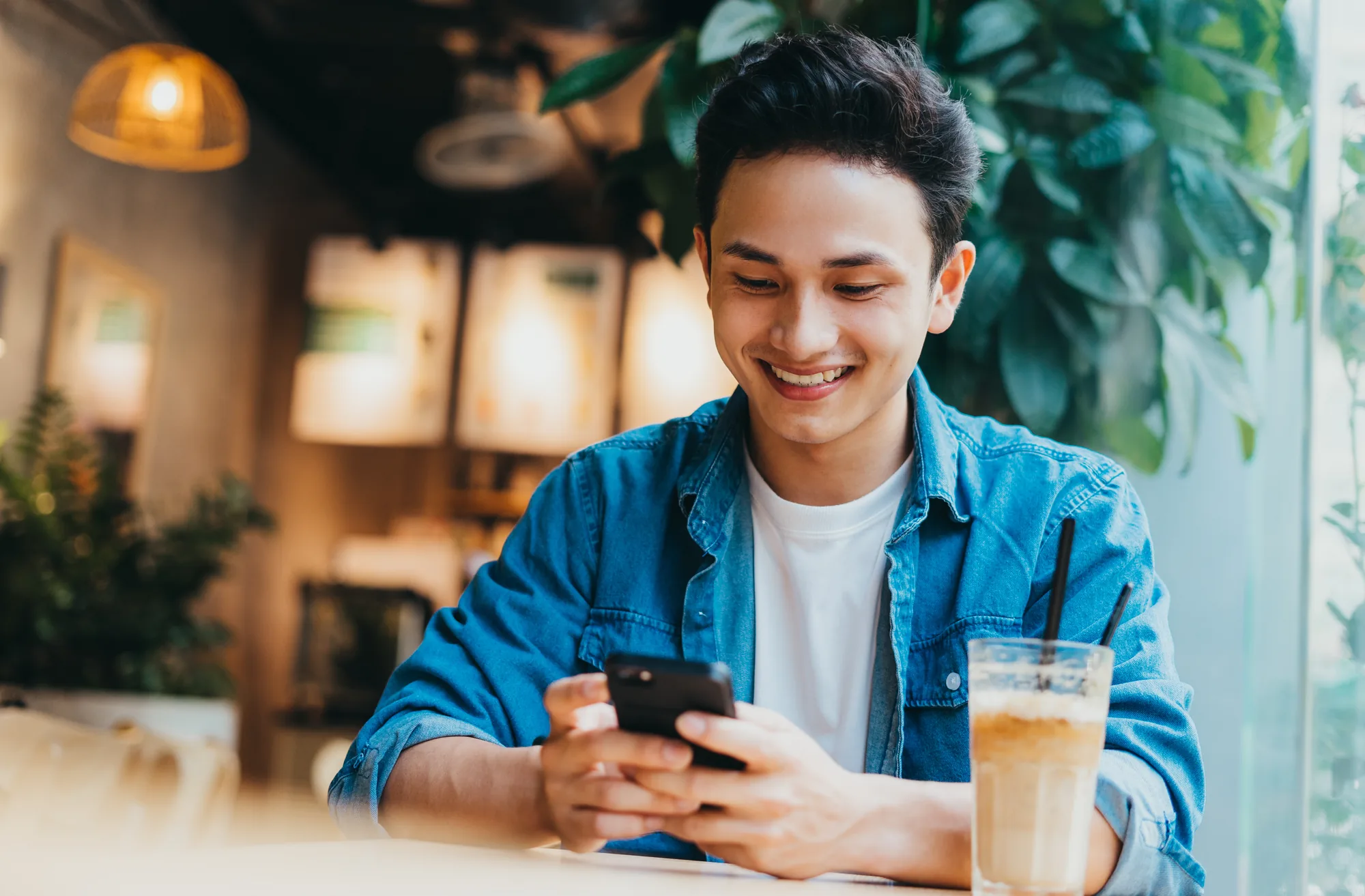Member managing his FREE Checking Account on his phone from a coffee shop